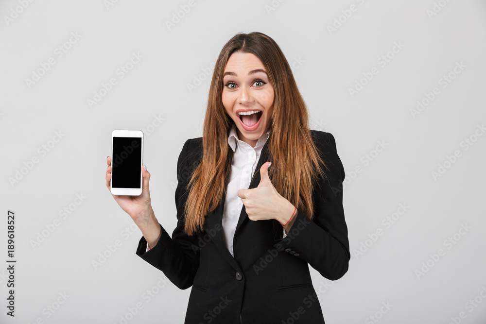 Surprised lady showing thumb up gesture and smartphone isolated Surprised lady showing thumb up gesture and smartphone isolated