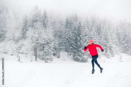 Woman trail running on snow in winter mountains