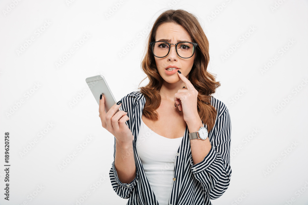 Portrait of an upset casual girl holding mobile phone