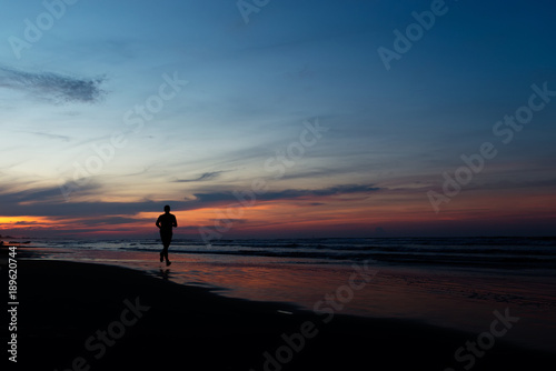 Silhouette of running man at sunset on the sea
