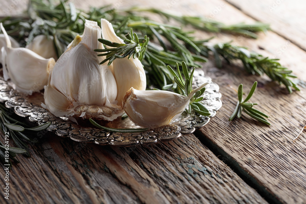Rosemary and garlic on a wooden table.