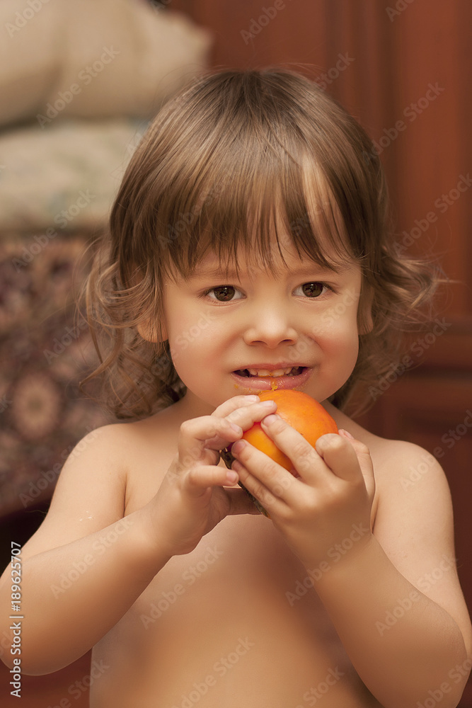small curly boy eating persimmon. Close-up portrait small curly boy eating persimmon. Close-up portrait