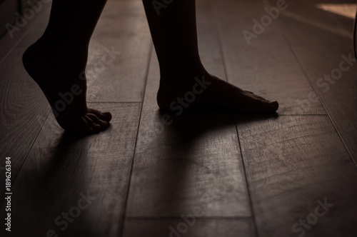 Woman's legs on a warm wooden floor