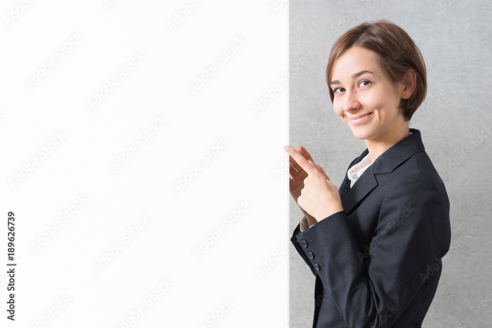 スーツ姿で案内する若い女性（コピースペース）