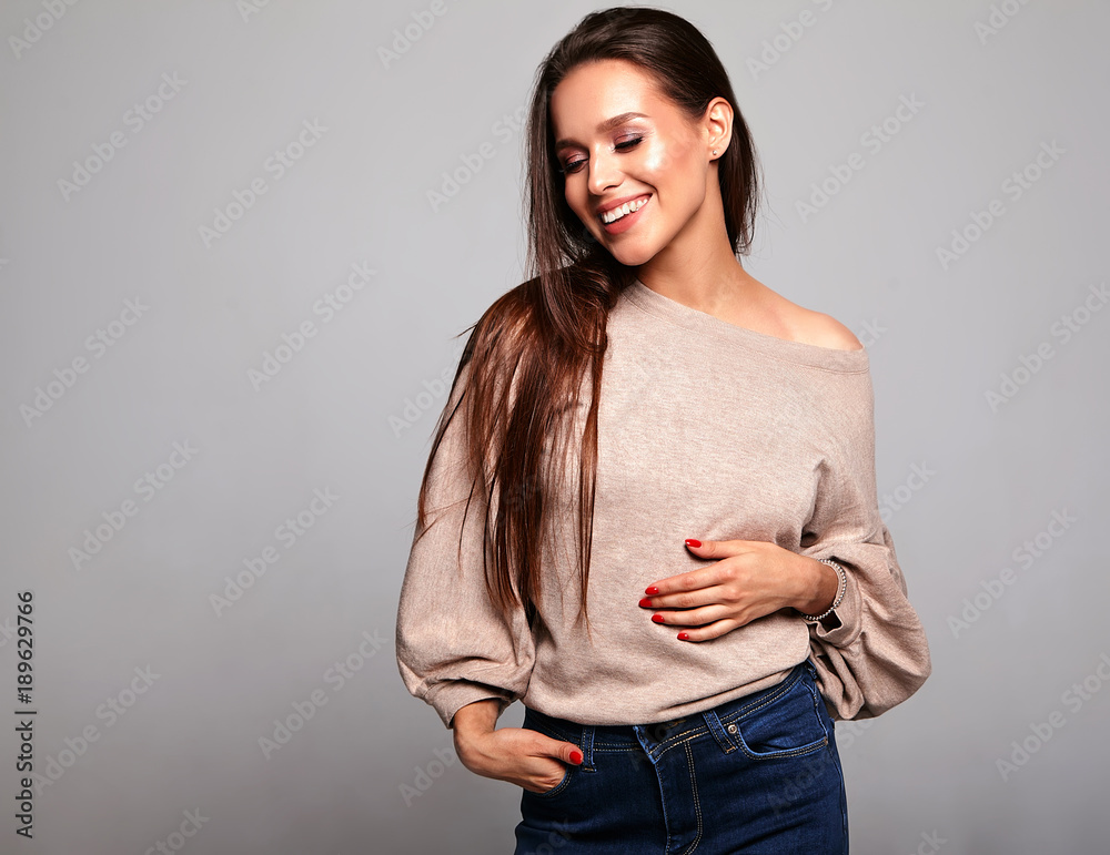 Obraz premium Portrait of beautiful smiling cute brunette woman model in casual beige warm sweater clothes with no makeup isolated on gray