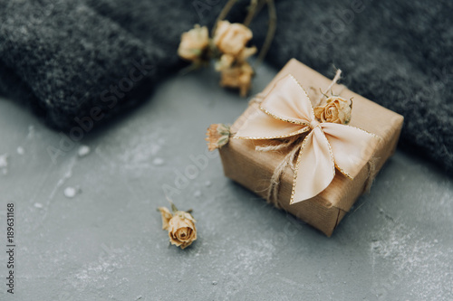 Wrapped gift box with dry flowers over blue background 