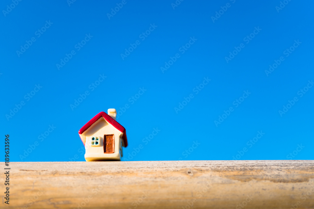Closeup miniature house on blue sky background using as property and family concept Closeup miniature house on blue sky background using as property and family concept
