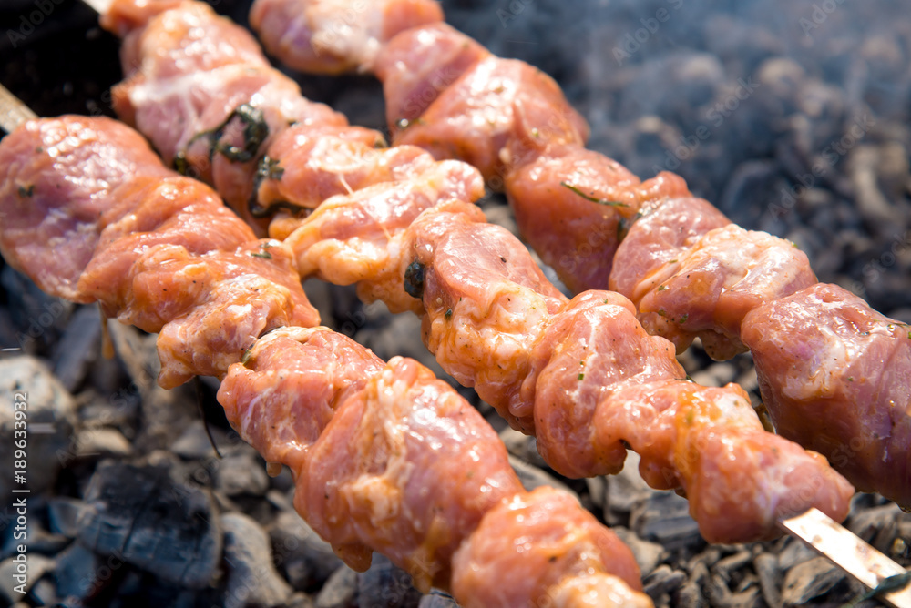 Marinated shashlik or Shish kebab preparing on a barbecue grill over charcoal.