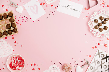 Valentine's Day, love concept. Mock up frame made of confetti, heart symbol accessories, sweets, postcards on pink background. Flat lay, top view.