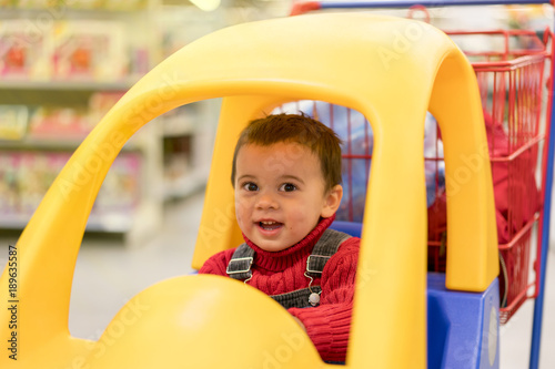 little cheerful boy in a trolley in a shopping center