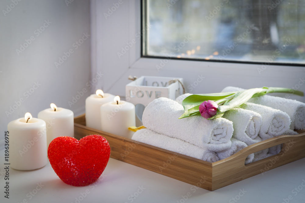 the Rolled hand towels on a tray next to the lighted candles and a bouquet of tulips in the spa salon