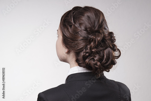 head of woman with brown hair in bun on gray isolated background rear view head turning to the left