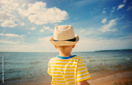 Boystanding at sea in straw hat photo