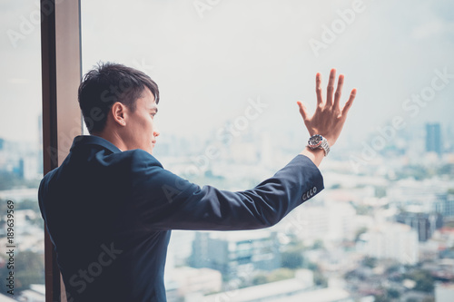 Happy young asian businessman in office looking out the window. concept for business