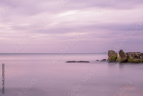 Sea open space and rocks in the water. Long exposure. Artistic photo, minimalism, simplicity and gentle lilac tones. © Ann Stryzhekin