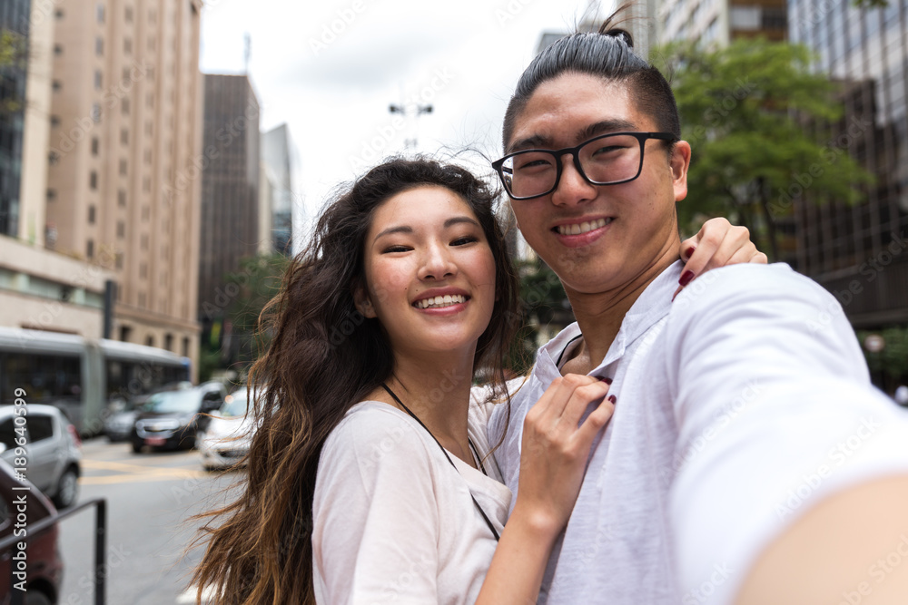 Young Asian Couple taking a selfie in Paulista Avenue, Sao Paulo, Brazil