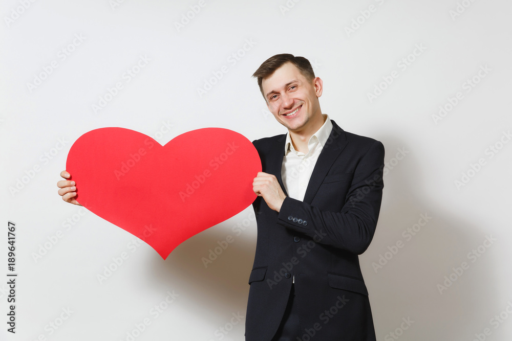 Young smiling man in suit holding big red heart isolated on white background. Copy space, advertisement. Place for text. St. Valentine's Day, International Women's Day, birthday, holiday concept. Young smiling man in suit holding big red heart isolated on white background. Copy space, advertisement. Place for text. St. Valentine's Day, International Women's Day, birthday, holiday concept.