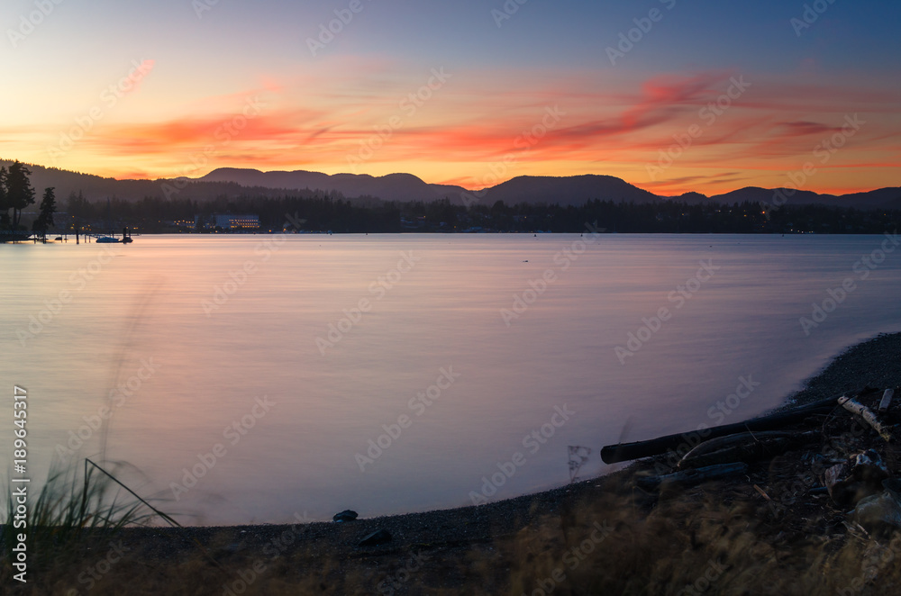 Spectacular sunset over a bay. Forested Mountain are Visible in Background. Sooke, Vancouver Island, BC, Canada.