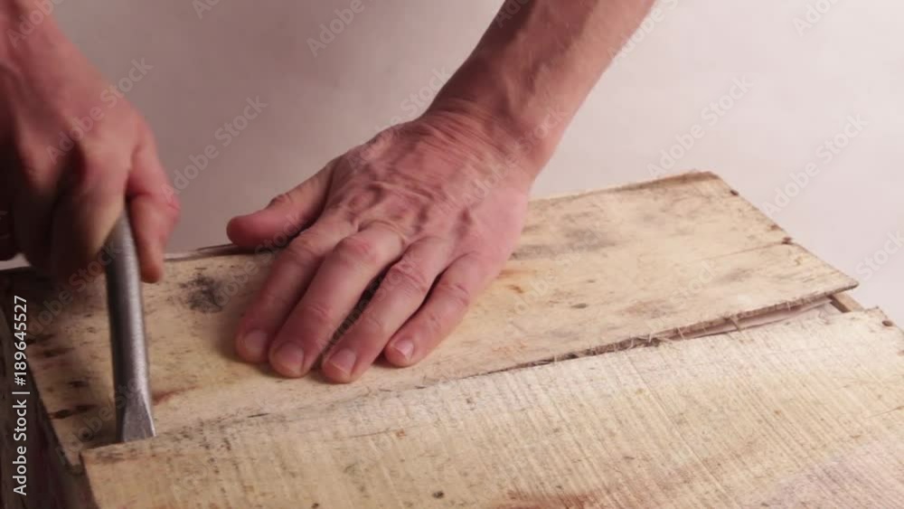 Close-up. Male hands with a wide screwdriver or other mounting tool open a wooden box. Breaking the first plank. Light background. Full HD unprocessed video. Close-up. Male hands with a wide screwdriver or other mounting tool open a wooden box. Breaking the first plank. Light background. Full HD unprocessed video.