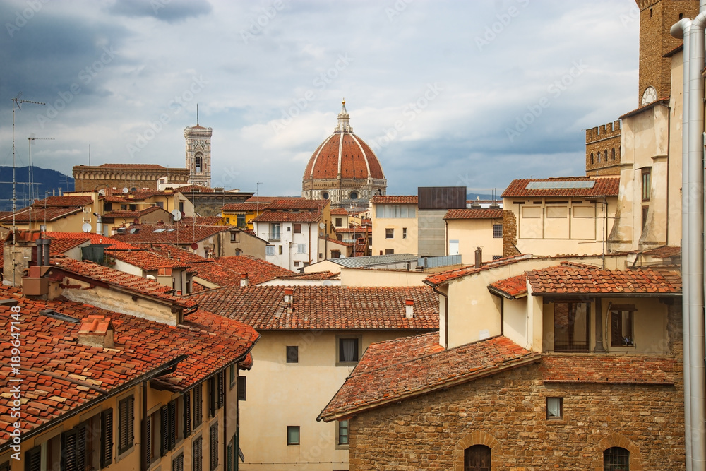 The urban landscape of Florence. Top view of the Cathedral of Saint Mary of the Flower and the tiled roofs of houses. Brick Dome of the Duomo over the roofs of the city. June 2017.
