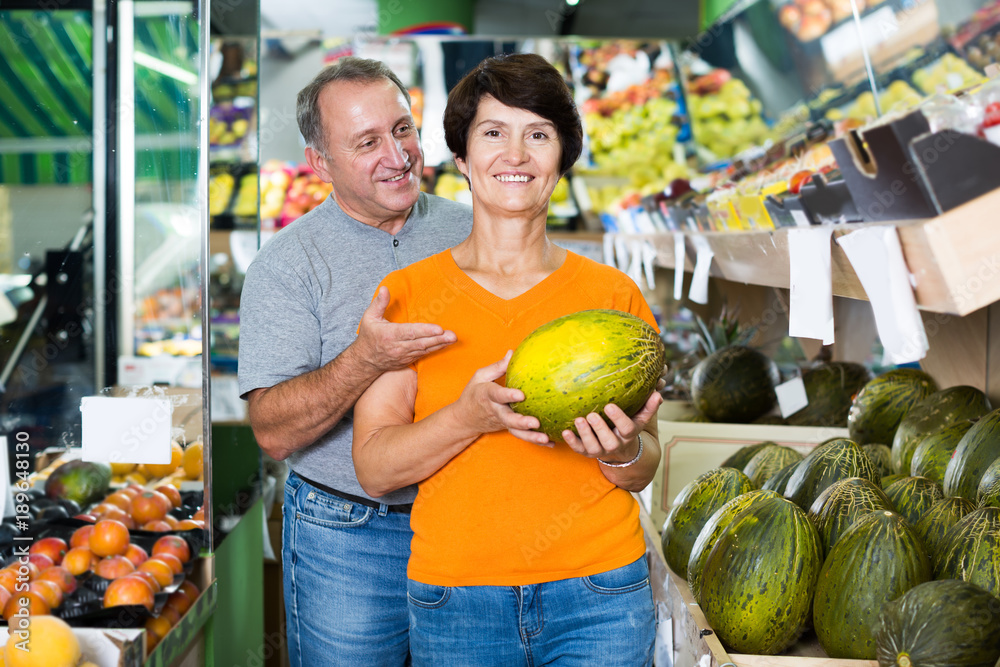 Fototapeta premium Adult man and his wife are choosing ripe melon
