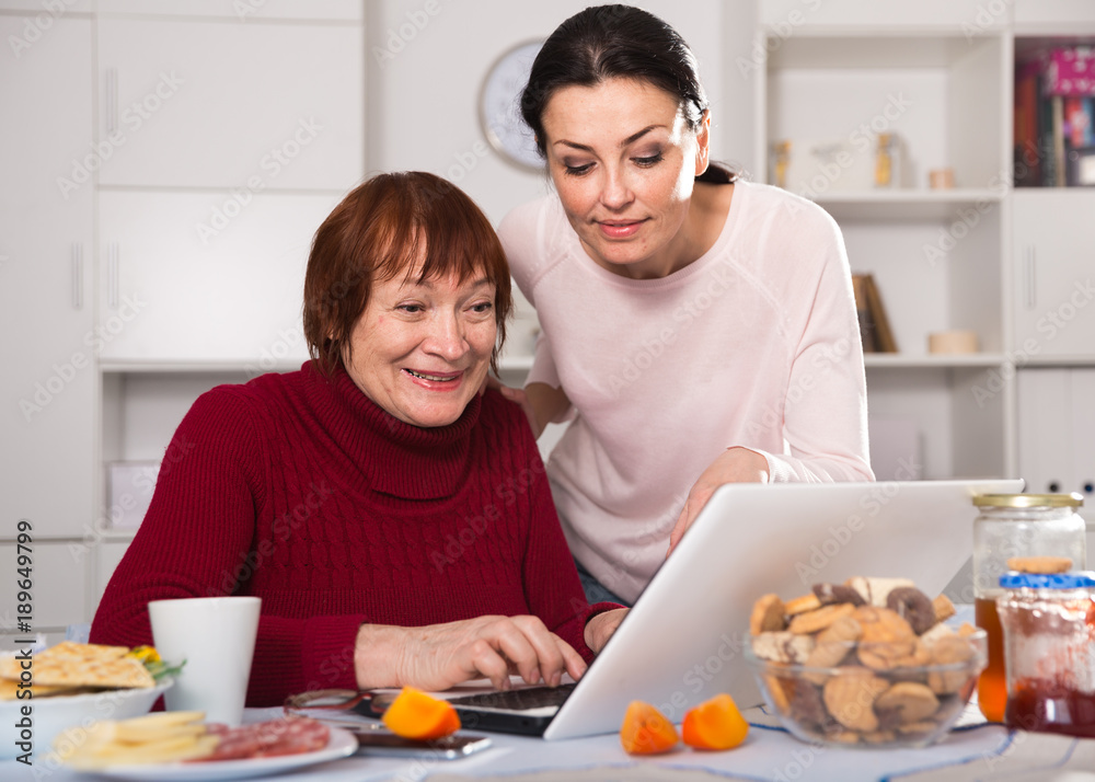 Mature women sitting and using laptop with  daughter