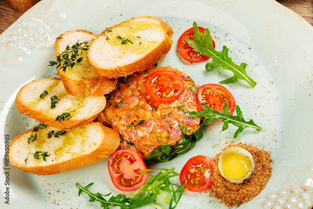 Beef tartare with egg yolk and tomato on table