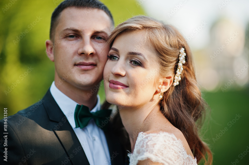 Lovely wedding couple walking along the green alley which leads to a church.