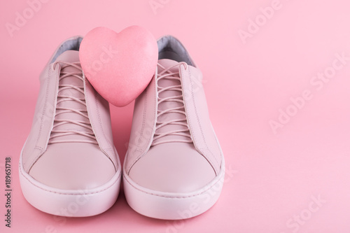 Soft colored women's sneakers on the pink background with heart symbol for the Valentine's Day or Shoe Sale