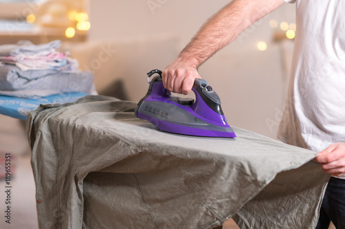Househusband, stay-at-home dad ironing clothes. Cropped image