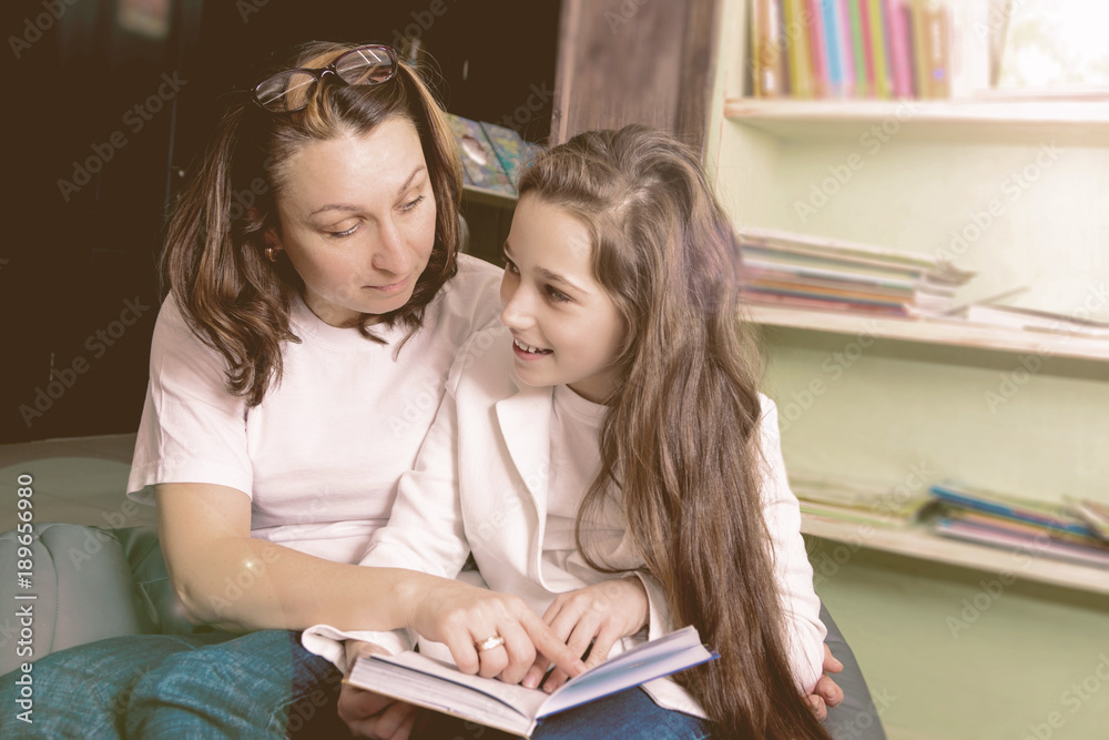 A friendly young woman with her cute little doughter are in a vintage book shop or store and cafe have fun, choose and read interesting books. Together. Concept of free time. A friendly young woman with her cute little doughter are in a vintage book shop or store and cafe have fun, choose and read interesting books. Together. Concept of free time.