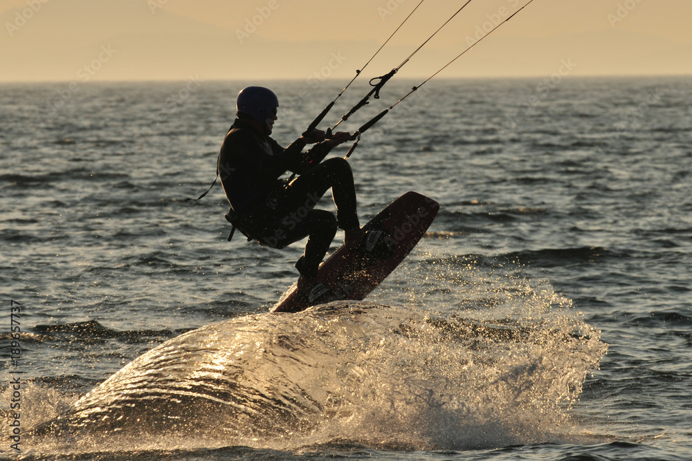 Naklejka premium Kitesurfer creating a wave while jumping