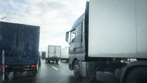 Big truck with refrigerator unit on reefer trailer transports commercial industrial cargo on a multi-lines highway with wet shiny coating and rain dust in rainy weather. photo
