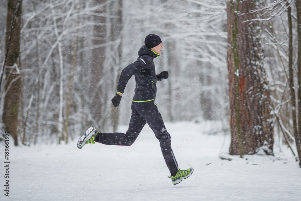 Photo from side of man in sports clothes on run in winter