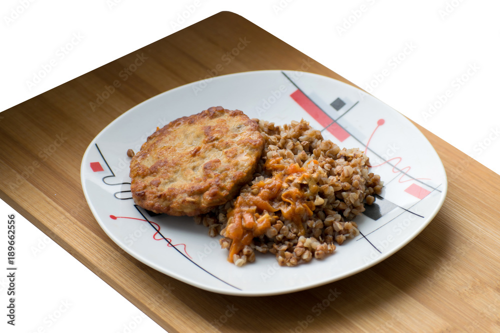Buckwheat porridge with a cutlet on a white plate. Buckwheat cereal with schnitzel on a wooden board.