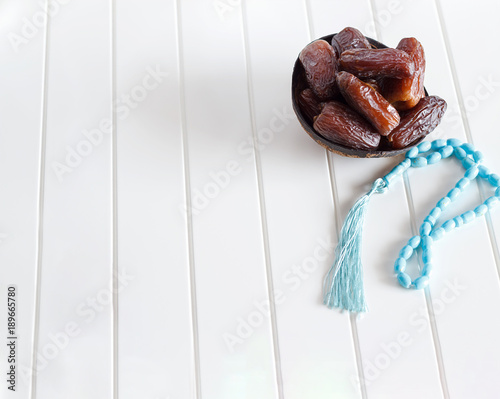 Organic dates Medjool in wooden coconut bowl and rosary. White background. Selective focus. Copy space. © alju