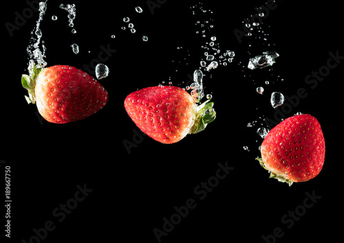 Strawberries in the water on black.