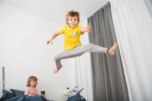 Cheerful little boy  jumping on bed at home
 photo