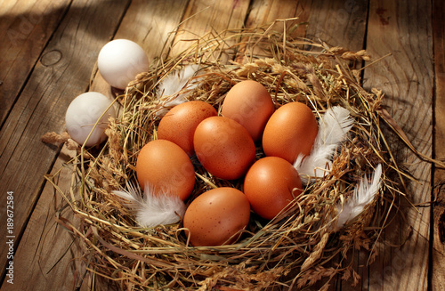 Hen organic eggs in the nest. On wooden rustic background.Copy space