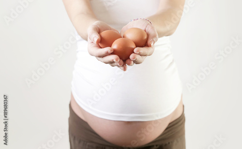 Pregnant woman holding eggs - studio shot