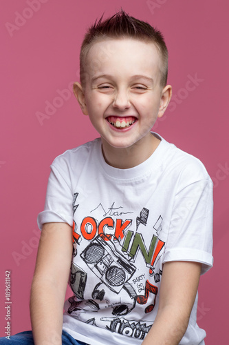 Happy boy laughing against a pink wall photo