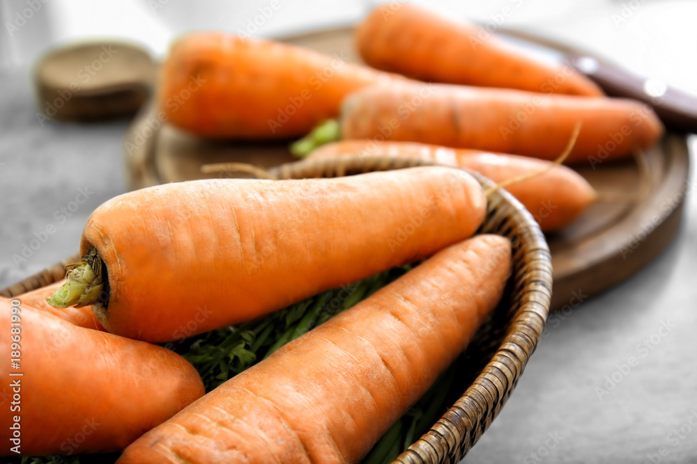 Wicker bowl with fresh carrots on table, closeup Wicker bowl with fresh carrots on table, closeup