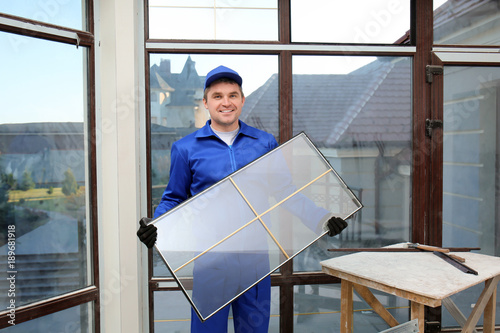 Foto Construction worker holding window glass indoors