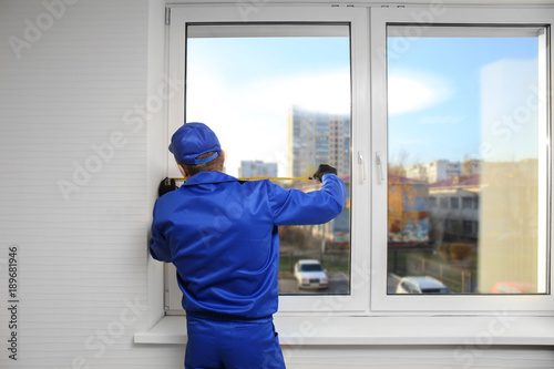 Construction worker repairing window in house