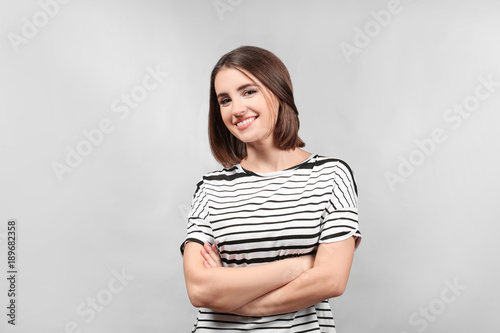 Portrait of young smiling woman on grey background