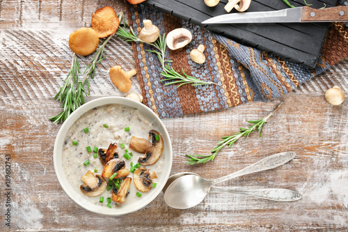 Bowl with delicious mushroom soup on wooden table