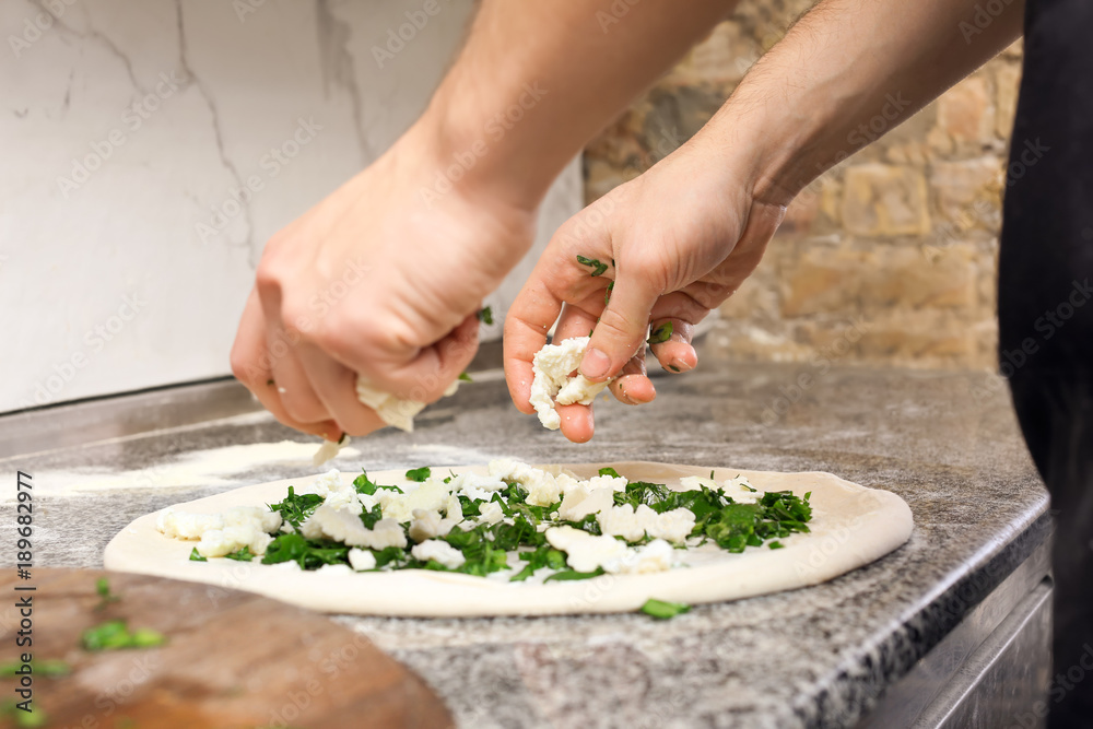 Chef making pizza at table in restaurant kitchen Chef making pizza at table in restaurant kitchen