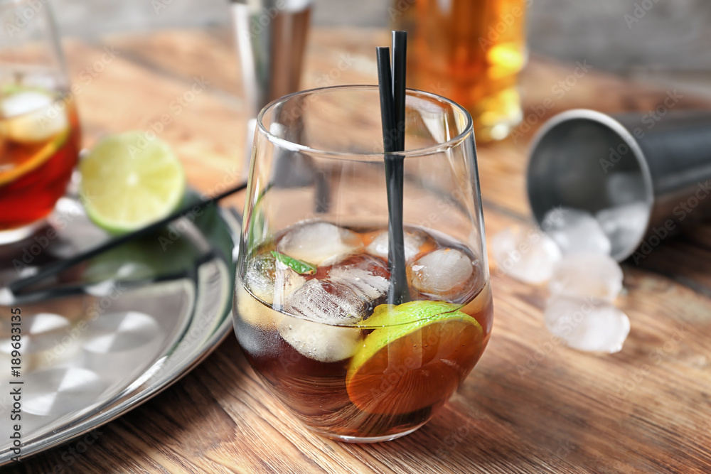 Glass of Cuba Libre cocktail on wooden table Glass of Cuba Libre cocktail on wooden table