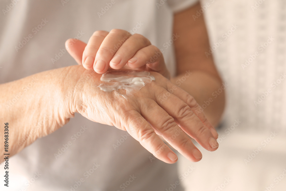 Senior woman applying hand cream, closeup Senior woman applying hand cream, closeup