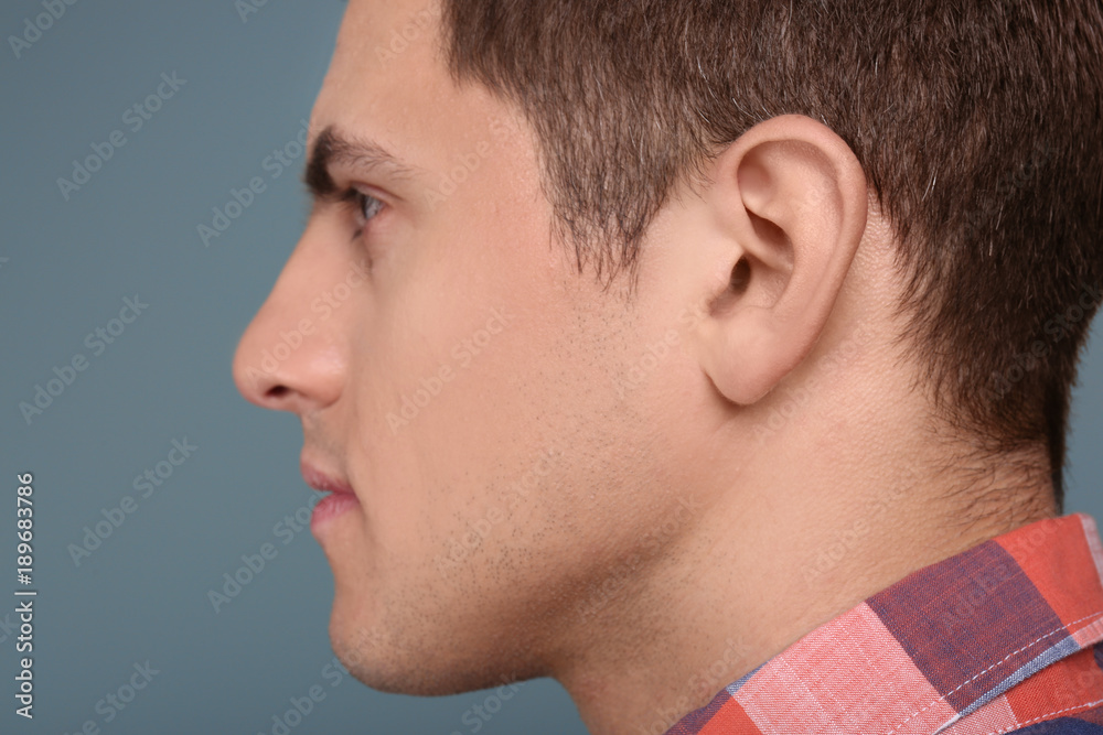 Young man on grey background. Hearing problem Young man on grey background. Hearing problem